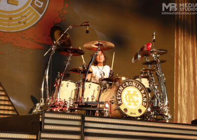 A drummer plays on a stage at the PNC Pavilion with a Ludwig bass drum featuring a Kevin Cronin Band logo.