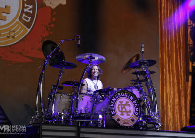 A drummer sits behind a Kevin Cronin Band drum kit on the PNC Pavilion stage during a concert.